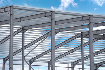 Construction of a steel structure against a blue sky with clouds at a building site during daytime