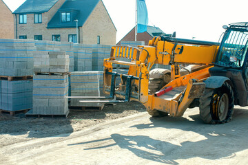 Telehandler with a flat tire on a worksite near concrete blocks during daytime