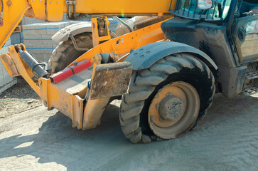 Telehandler with a flat tire on a worksite near concrete blocks during daytime © Iryna