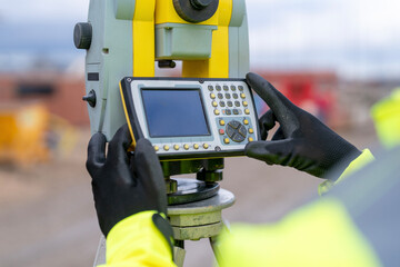 Construction worker surveyor using surveying equipment in a field during daylight hours for precise...