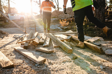 Builders sorting and checking wooden planks on the ground.