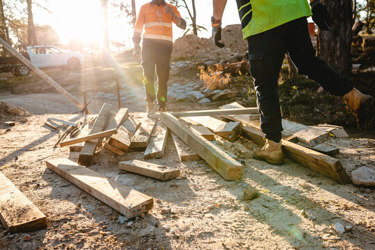 Builders sorting and checking wooden planks on the ground.
