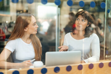 Two women engaged in a lively conversation over coffee at a cafe during the afternoon