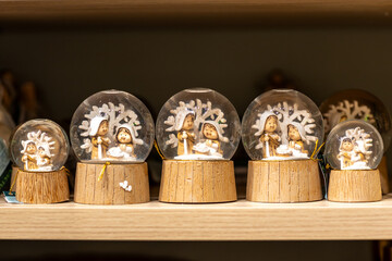 Close-up of Christmas snow globes on store shelves, standing in a row.