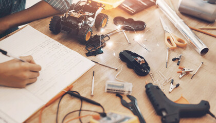 Hands, notebook and person with robotics for education with machine learning for school project. Electronic vehicle, tools and engineering student with stem equipment for car circuit building at home