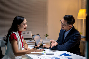 Asian business people having business meeting using digital tablet and documents at office night time