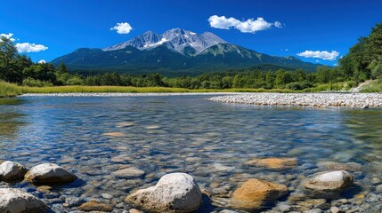 A calm river flows through a valley with a majestic mountain in the background, under a blue sky with white clouds.