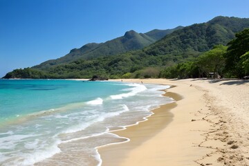 Pristine beach with clear water and lush mountain backdrop under a blue sky