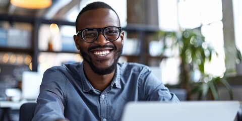 Naklejka premium Businessman with laptop and credit card smiling in an office, engaging in online shopping and digital transactions. Professional enjoying e-commerce and financial activities