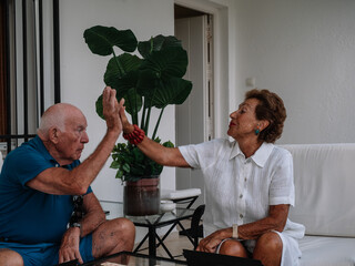 Marriage octogenarian play animatedly to a board game consisting of making combinations of numbers