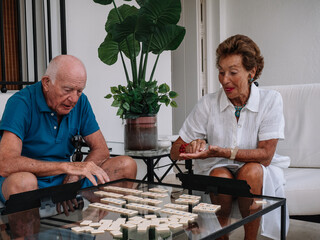 Marriage octogenarian play animatedly to a board game consisting of making combinations of numbers