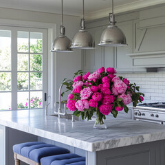 Modern kitchen with marble island countertop, gray cabinets, and a vibrant bouquet of pink peonies, creating a bright and inviting space with natural light and stylish decor
