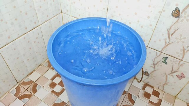 Filling the blue bathtub with running water from the tap in the bathroom