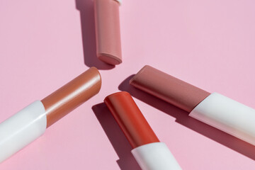 Various lipstick shades on a pink background in natural light