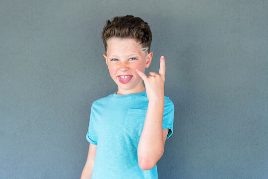 Playful boy making a rock gesture with a mischievous smile