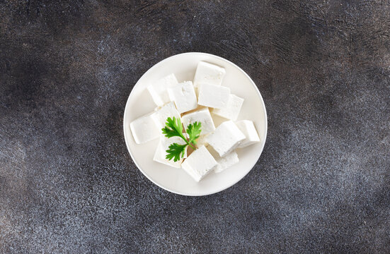 Indian paneer cheese made from fresh milk and lemon juice, cut into cubes on grey background. Top view. Copy space