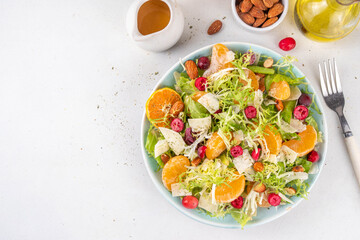 Salad bowl with lettuce, tangerines, nuts and cranberry
