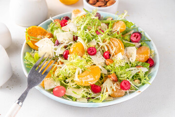 Salad bowl with lettuce, tangerines, nuts and cranberry
