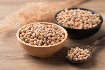 Soy bean seeds in wooden bowl with spoon on wooden background, Food ingredient