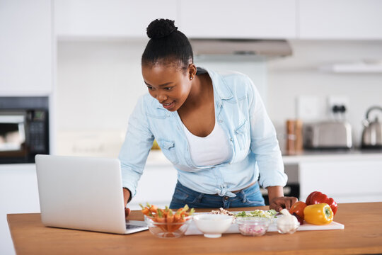 Black woman, laptop and cooking meal in kitchen, search online recipe and vegetables for nutrition. Female person, ingredients and food in home, vegan cuisine and meal prep or reading instructions