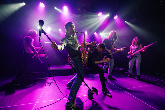 Music band playing live on stage with purple lights