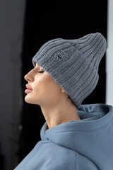 Portrait beautiful woman in grey hat. Pretty girl in warm clothes on black background. Studio photography. Vertical photo. High quality photo