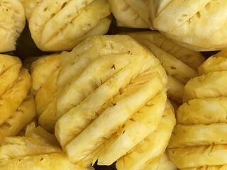 Sliced pineapple pieces arranged closely, showcasing their vibrant yellow color and textured surface.