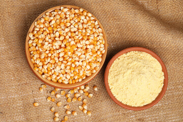 Corn flour in terracotta bowl  with corn on jute background