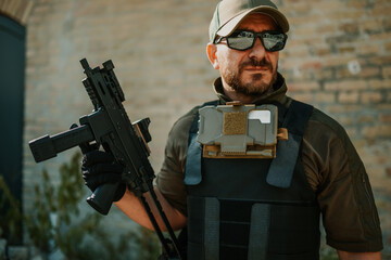 Obraz premium Soldier holding submachine gun and wearing tactical vest and sunglasses