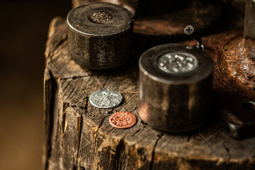 An old coin minting press on a wooden stump, bathed in sunlight. The freshly minted coins are visible, highlighting the age-old technique of coin engraving and the beauty of traditional craftsmanship.