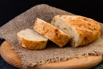 Sliced wheat bread with seeds on dark background.