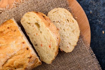 Sliced wheat bread with seeds on dark background.