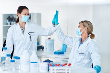 Women, scientist and high five in lab with celebration, face mask and success with results at...