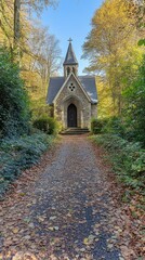 Fototapeta premium A quaint stone chapel surrounded by autumn foliage on a leaf-covered path.