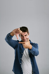 Man, happy and finger frame in studio with photography icon with fashion by white background. Person, model and shape with hands, perspective and smile with mock up space for sign, emoji and view