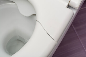 A broken toilet seat with visible cracks, photographed from above, close-up view
