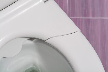 A broken toilet seat with visible cracks, photographed from above, close-up view