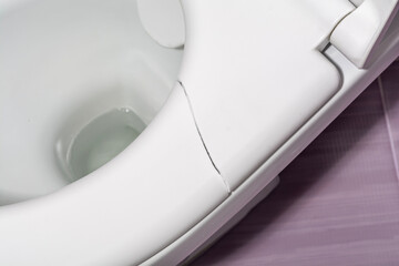 A broken toilet seat with visible cracks, photographed from above, close-up view