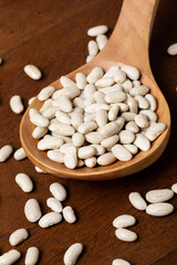White beans in a spoon on a wooden table