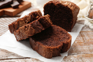 Delicious cut chocolate sponge cake on wooden table, closeup
