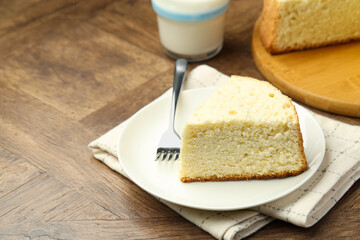 Piece of delicious sponge cake and fork on wooden table