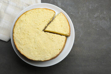 Delicious cut sponge cake on grey textured table, top view. Space for text