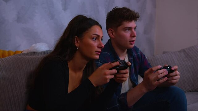 Cute couple playing video games intensely both of them lose the game and fall back into the chair