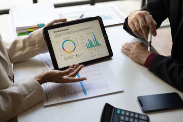 Meetings discuss business situations by analyzing financial charts in company reports on digital...