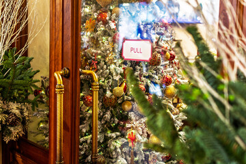 Entrance to a store decorated for Christmas holidays, adorned with a Christmas tree with gold and red ornaments, festive New Year atmosphere