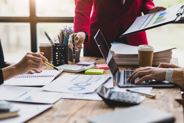 Meeting of business women analyzing financial charts and planning marketing together. Meeting to share ideas with colleagues in a conference room.