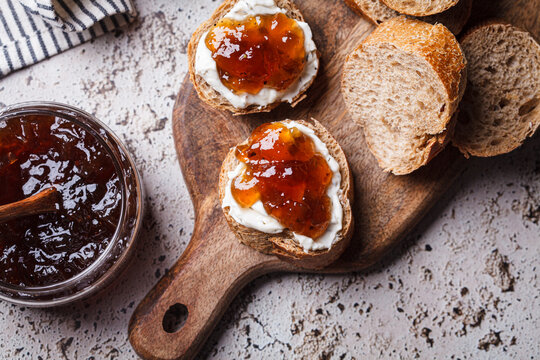 Onion jam on toast with cream cheese, gray background.