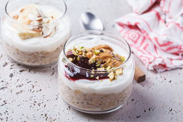 Overnight oatmeal with peanut butter, banana, nuts and jam in jars.