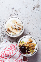 Overnight oatmeal with peanut butter, banana, nuts and jam in jars.
