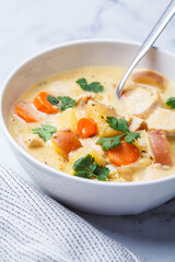 Chicken breast stew with potatoes and carrots in white bowl. Comfort food concept.